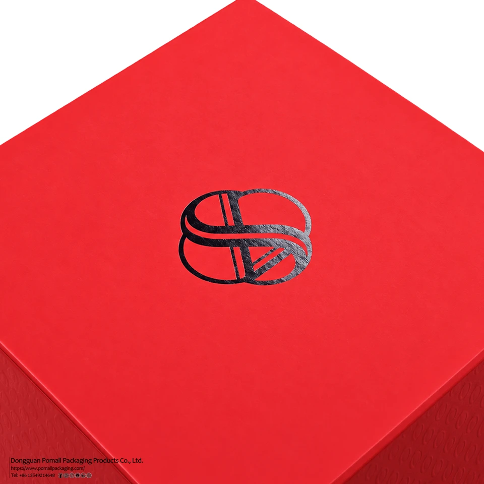 Black foil stamped logo detail on red rigid apparel gift box Black foil stamped logo detail on red rigid apparel gift box